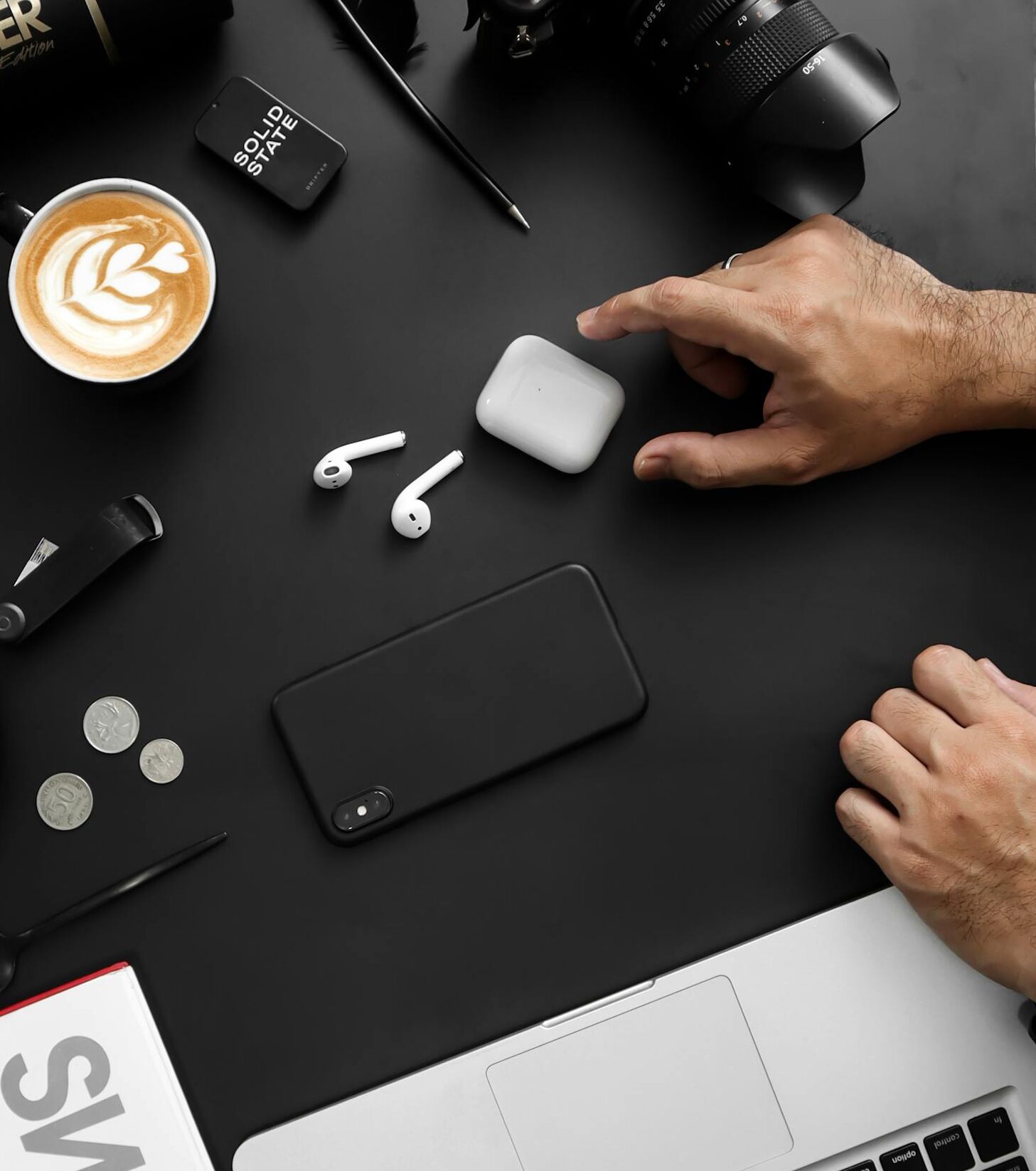 A contemporary workspace featuring tech devices, coffee, and a stylish magazine.