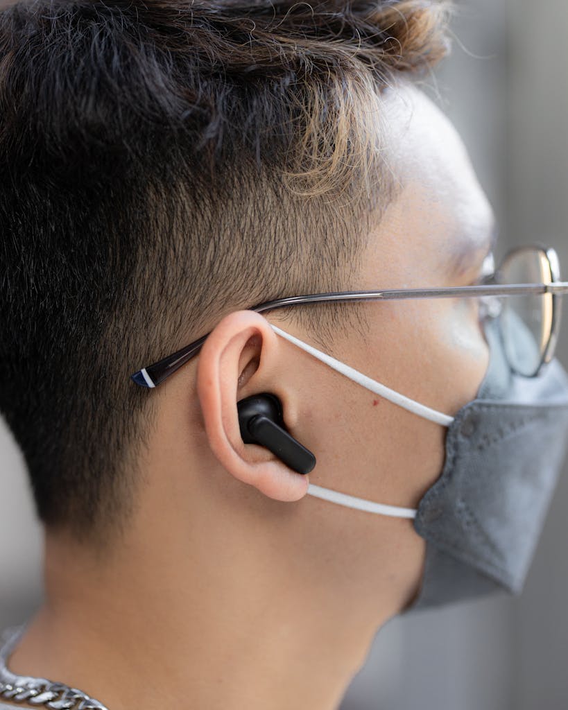 Side profile of a young man wearing TOZO T10 wireless earbuds with eyeglasses